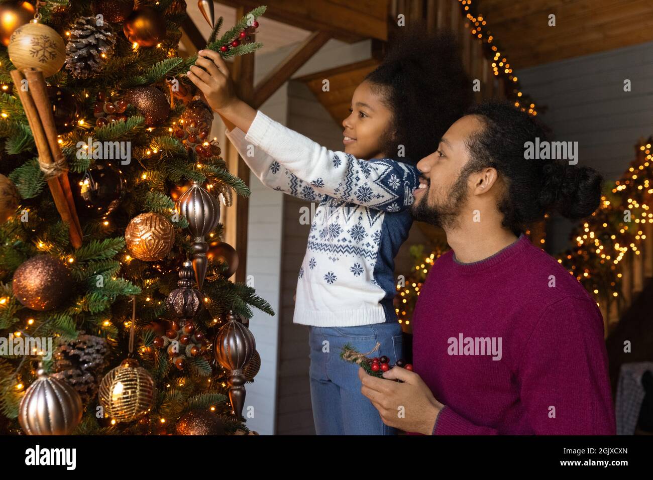 Bambina aiutare papà decorare abete albero per Natale Foto Stock