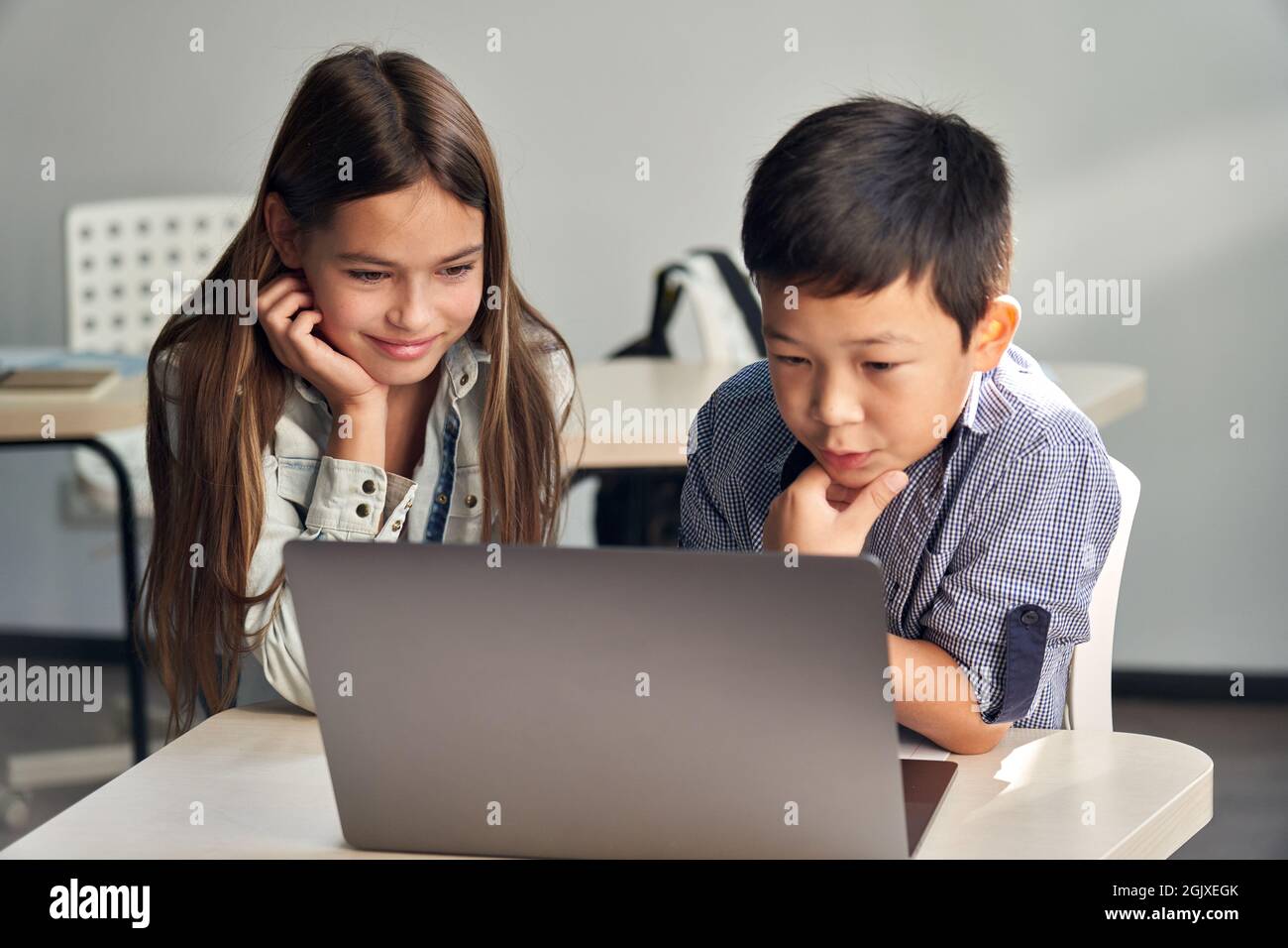 Due scolari diversi guardano i video di apprendimento insieme su un portatile. Foto Stock