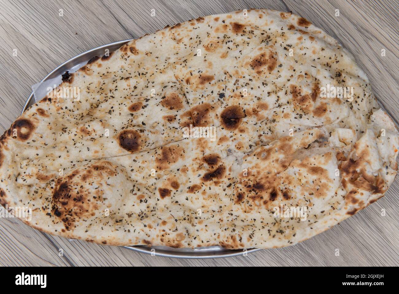 Vista dall'alto di pane naan aromatizzato all'aglio dal ristorante indiano cucinato e condito perfettamente. Foto Stock