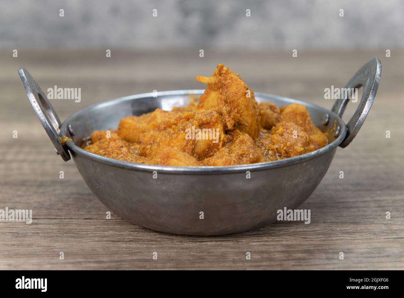 Carne di pollo aromatizzata al curry in una ciotola del ristorante indiano cucinata e condita perfettamente. Foto Stock