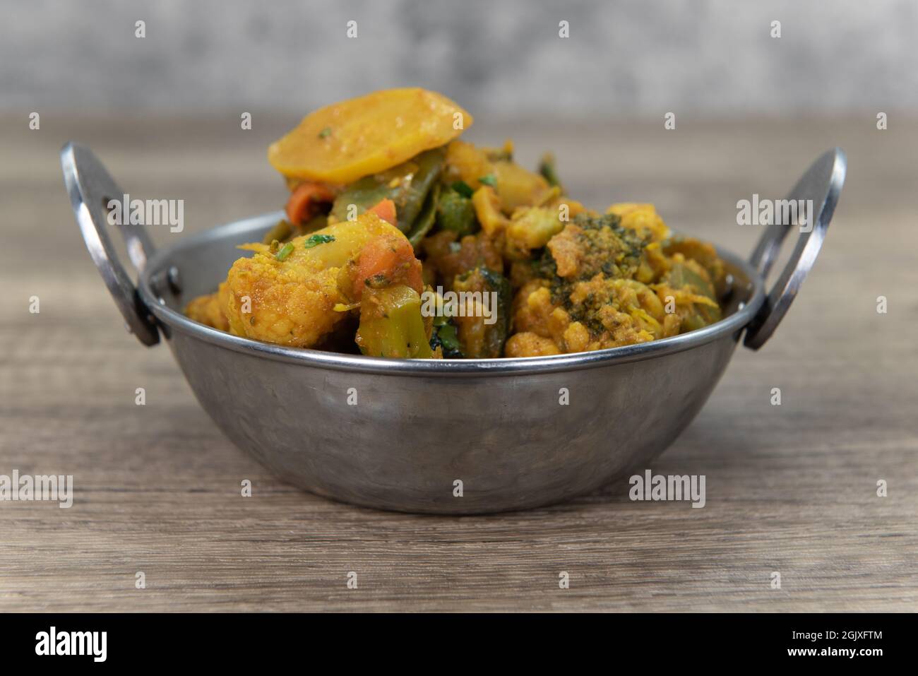 Verdure aromatizzate al curry in una ciotola del ristorante indiano cucinate e condite perfettamente. Foto Stock