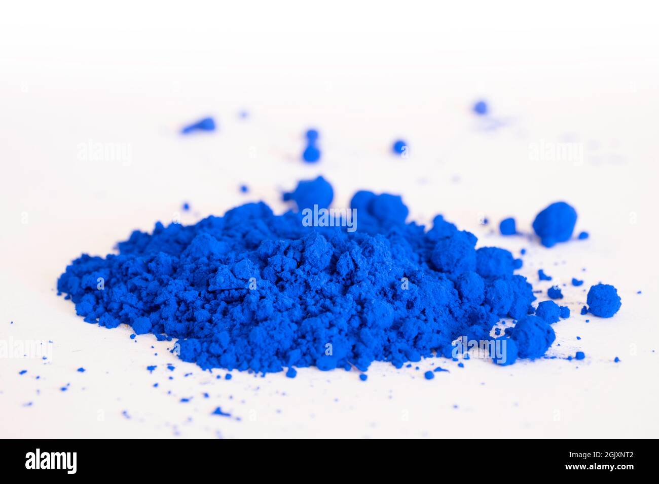 Primo piano di una porzione di pigmento blu isolato su bianco nella vista laterale. Il pigmento sarà mescolato con olio di lino per fare vernice di olio. Messa a fuoco selettiva Foto Stock