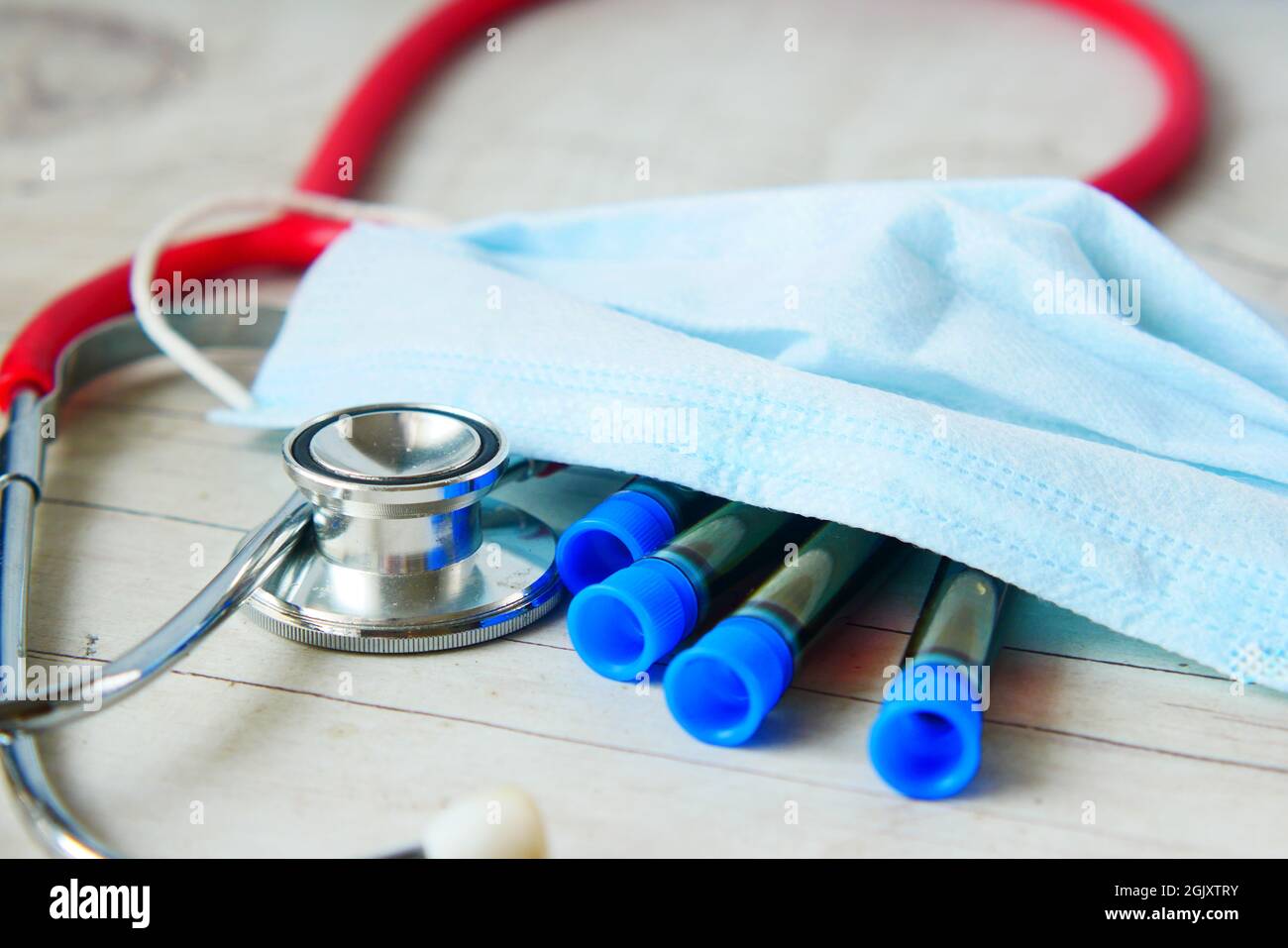 provetta per analisi del sangue del virus corona, stetoscopio e maschera sul tavolo Foto Stock