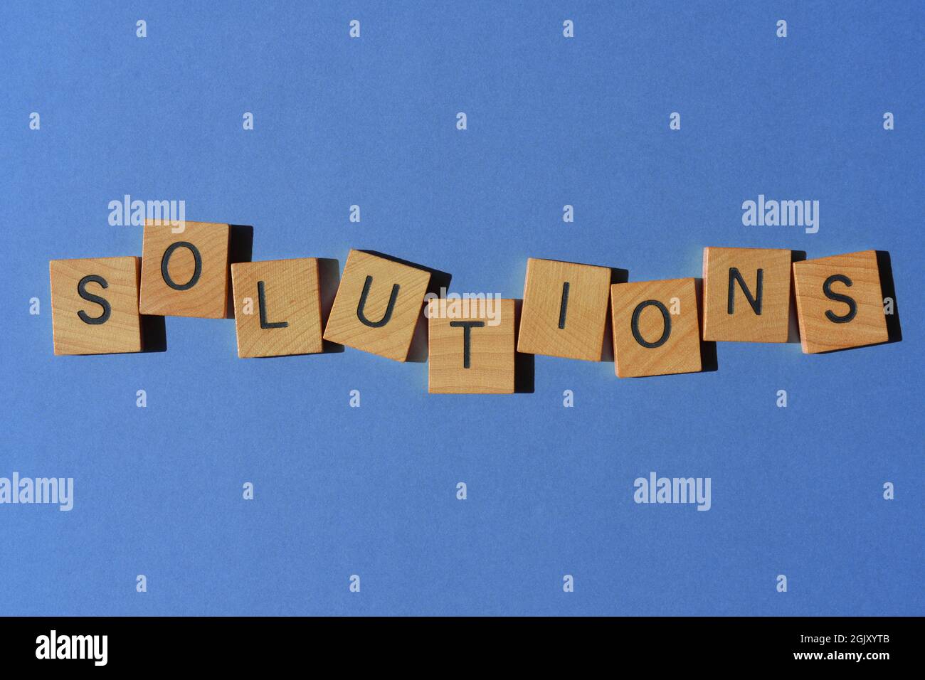 Soluzioni, parola in lettere di legno alfabeto isolato su sfondo viola come titolo banner Foto Stock