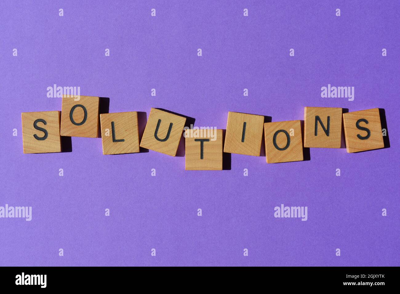 Soluzioni, parola in lettere di legno alfabeto isolato su sfondo viola come titolo banner Foto Stock