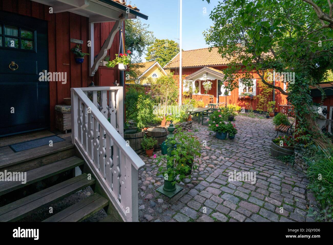 Vastervik, Svezia - 08.23.2021: Ampio giardino di vecchia casa in legno rosso tradizionale in stile scandinavo. Giornata estiva soleggiata nel piccolo giardino della città. Foto Stock