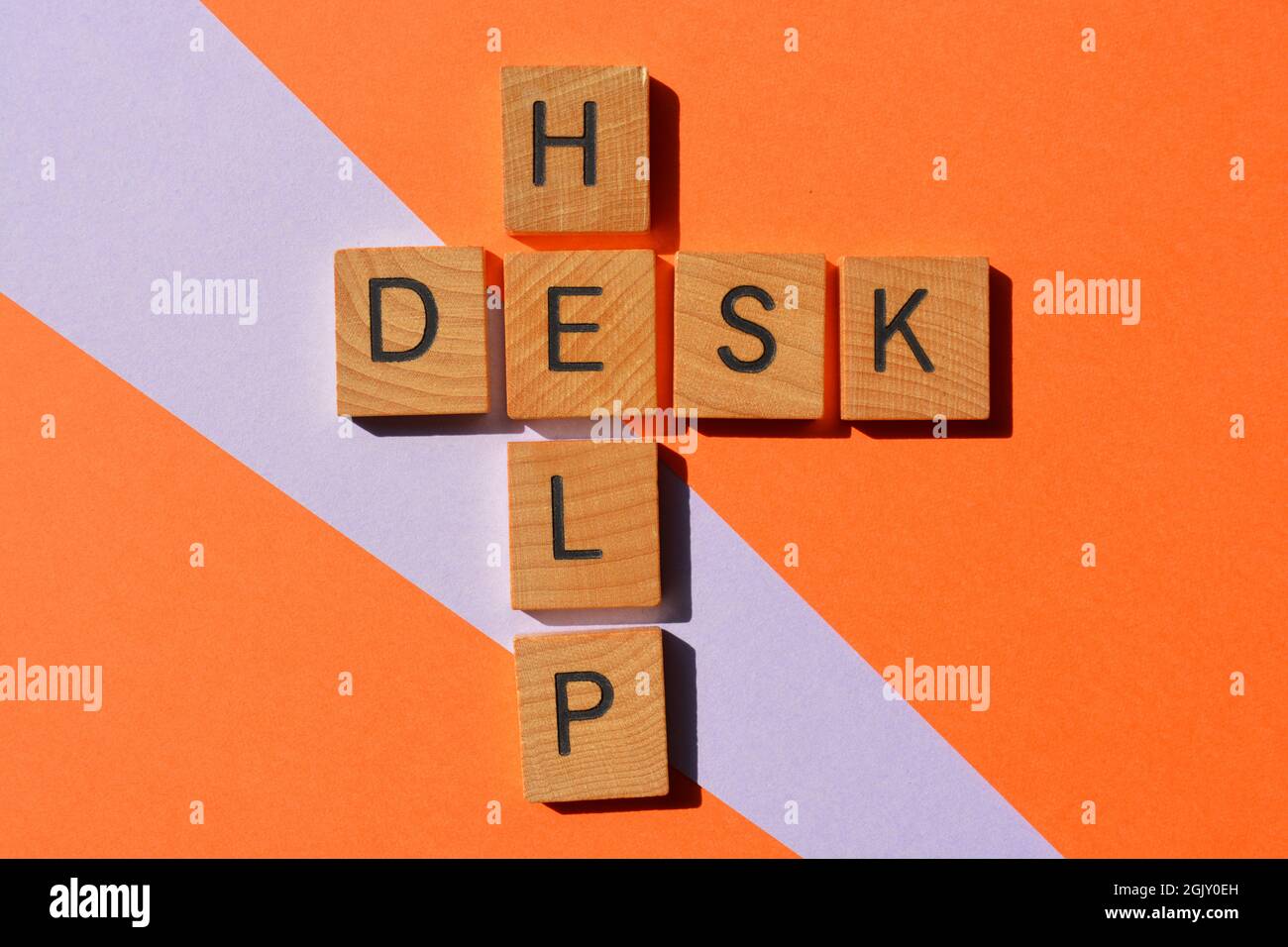Help Desk, parole in lettere in legno alfabeto in forma di parola incrociata isolato su sfondo arancione e malva Foto Stock