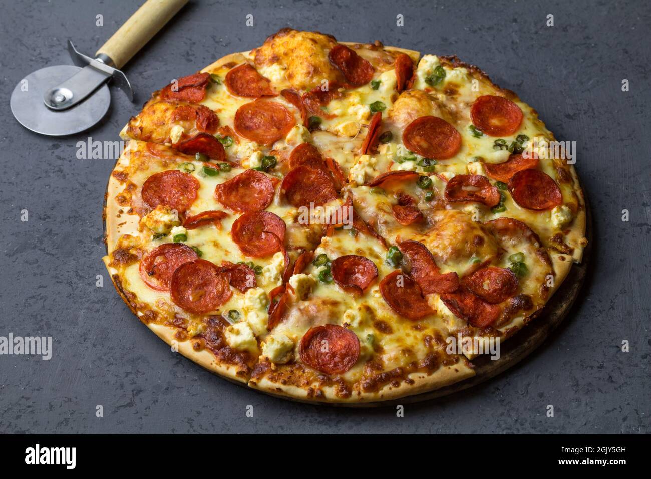 Gustosa pizza di peperoni a base di salame, feta, peperoni cileni su fondo di cemento nero. Vista dall'alto della pizza piccante di peperoni. Con spazio di copia per il testo. Foto Stock