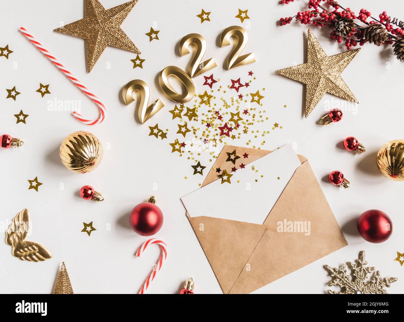 Busta marrone aperta con carta bianca vuota e varie stelle con i numeri di 2022 per l'anno prossimo imitazione di esplosione e festivo stagionale d Foto Stock