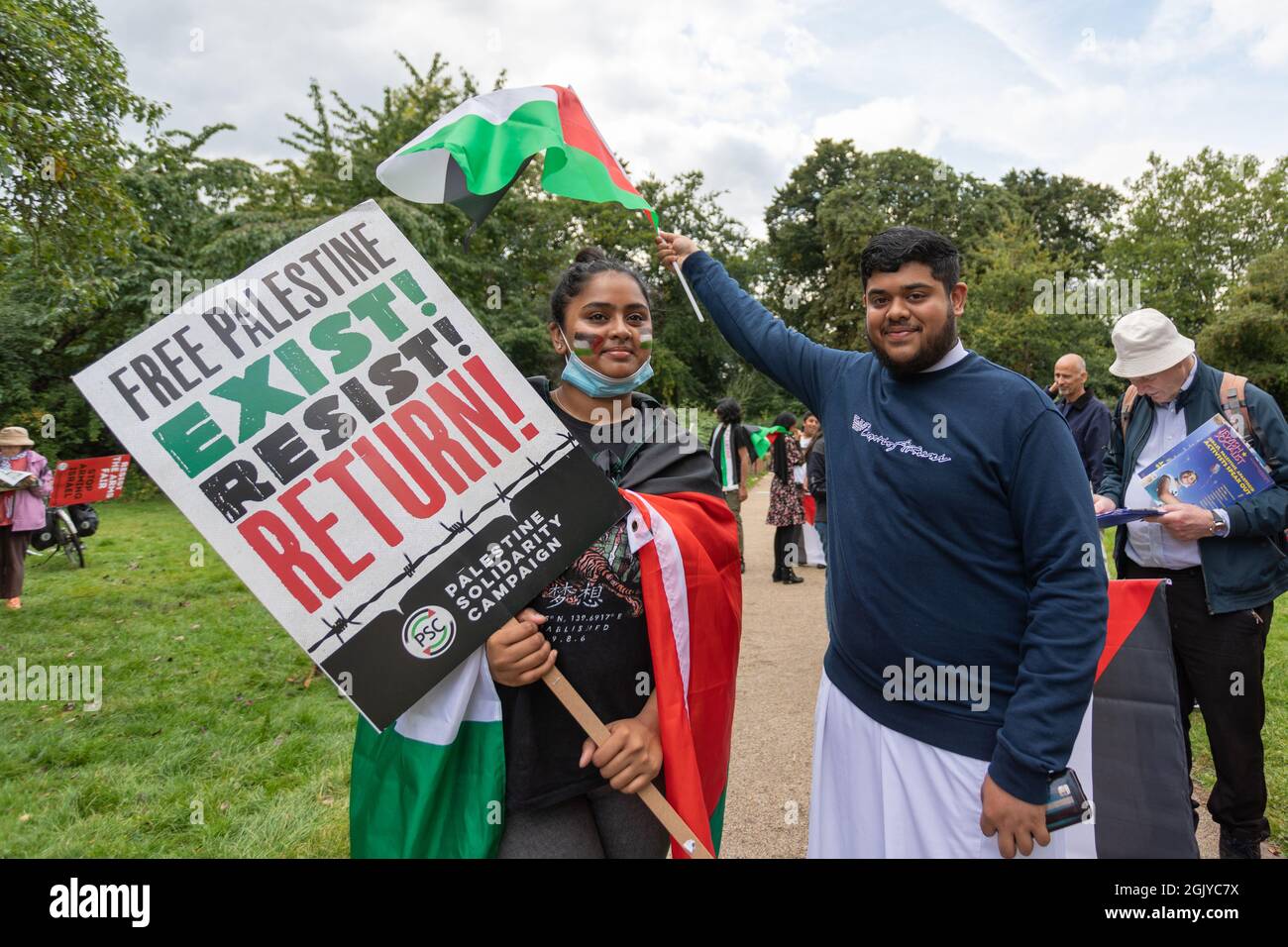 12 settembre 2021. Londra, Regno Unito. Due persone partecipano a una dimostrazione filo-palestinese in un parco Walthamstow. Uno ha un cartello che dice "PALESTINA LIBERA - ESISTE! RESISTI! TORNATE!” Ed è drappeggiato in una bandiera palestinese, mentre gli altri gesti verso la bandiera. Il raduno comprende altri partecipanti che tengono cartelli e opuscoli, che riflettono l'azione civica collettiva e l'attivismo dei giovani. Una marcia di protesta a Walthamstow, per smettere di armare Israele. Marzo è organizzato dalla campagna di solidarietà della Palestina. Penelope Barritt/Alamy Live News Foto Stock