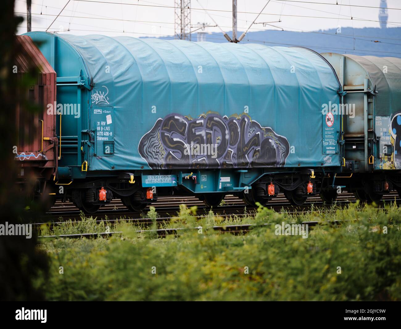 Carro merci coperto blu con graffiti in piedi su binari ferroviari in uno scalo ferroviario industriale. Foto Stock