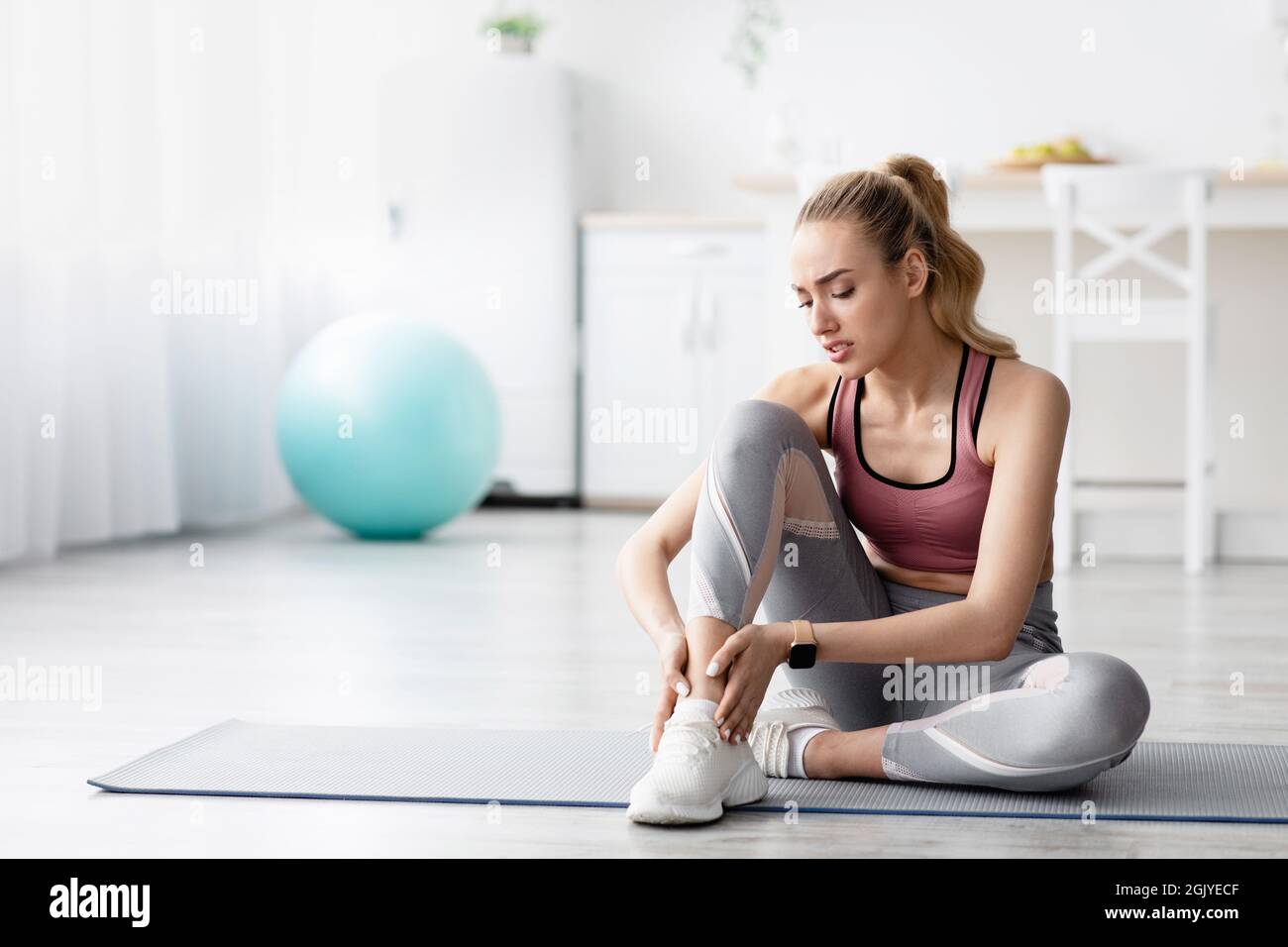 Depressione giovane donna bionda caucasica che soffre di dolore, sensazione di dolore alla gamba dopo l'allenamento Foto Stock