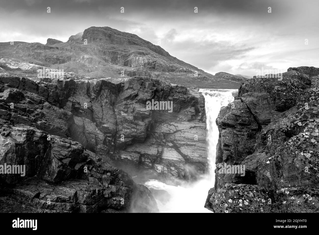 Primo piano, ampio, nero e bianco basso angolo di scatto della possente cascata Stuor Muorkkegarttje sul fiume Lulealven in una giornata poco nuvolosa di estate artica Foto Stock
