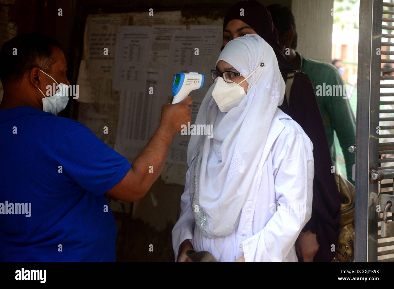 Dhaka, Bangladesh. Settembre 12, 2021. Un funzionario controlla la temperatura corporea di uno studente al suo arrivo alla scuola e al college delle ragazze del governo di Azimpur a Dhaka, Bangladesh, il 12 settembre 2021. Dopo 543 giorni, le scuole primarie, secondarie e superiori in tutto il paese riaprirono mantenendo le linee guida e i protocolli sanitari del Covid-19. Credit: Mamunur Rashid/Alamy Live News Foto Stock