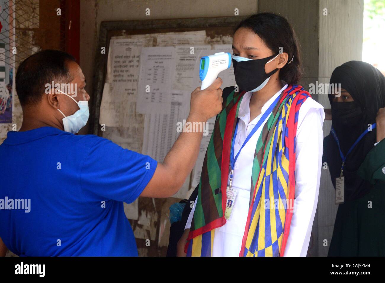 Dhaka, Bangladesh. Settembre 12, 2021. Un funzionario controlla la temperatura corporea di uno studente al suo arrivo alla scuola e al college delle ragazze del governo di Azimpur a Dhaka, Bangladesh, il 12 settembre 2021. Dopo 543 giorni, le scuole primarie, secondarie e superiori in tutto il paese riaprirono mantenendo le linee guida e i protocolli sanitari del Covid-19. Credit: Mamunur Rashid/Alamy Live News Foto Stock