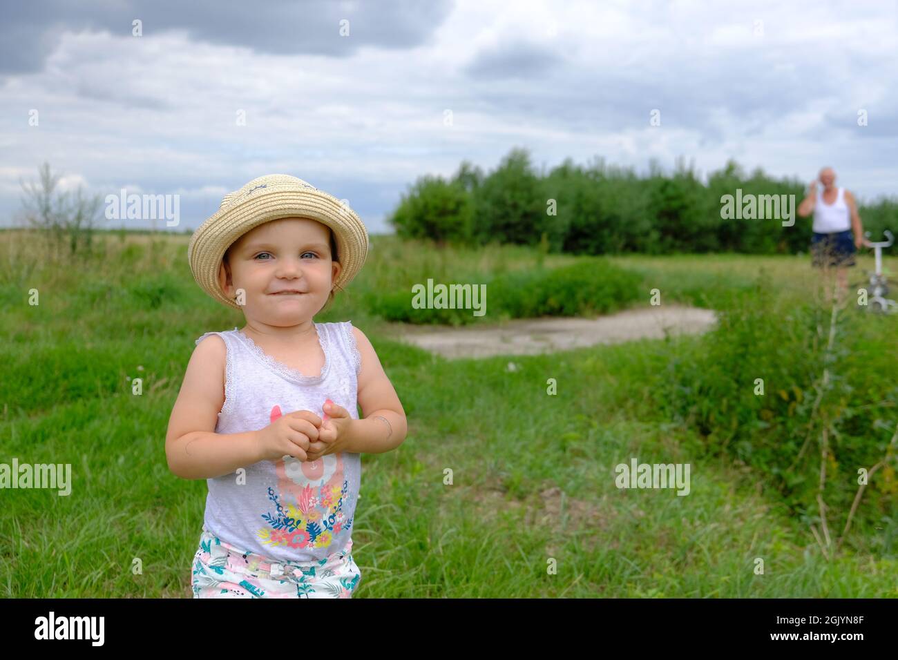 Ritratto di una bambina sorridente in un cappello estivo in piedi in un prato verde in Polonia Foto Stock
