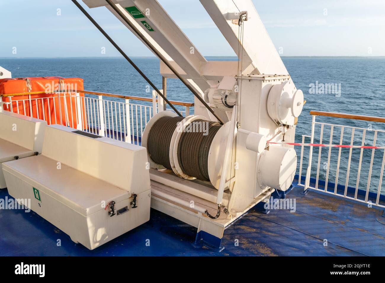 Mulinello in acciaio di una gru su un ponte di barca a vela con orizzonte marino sullo sfondo. Foto Stock