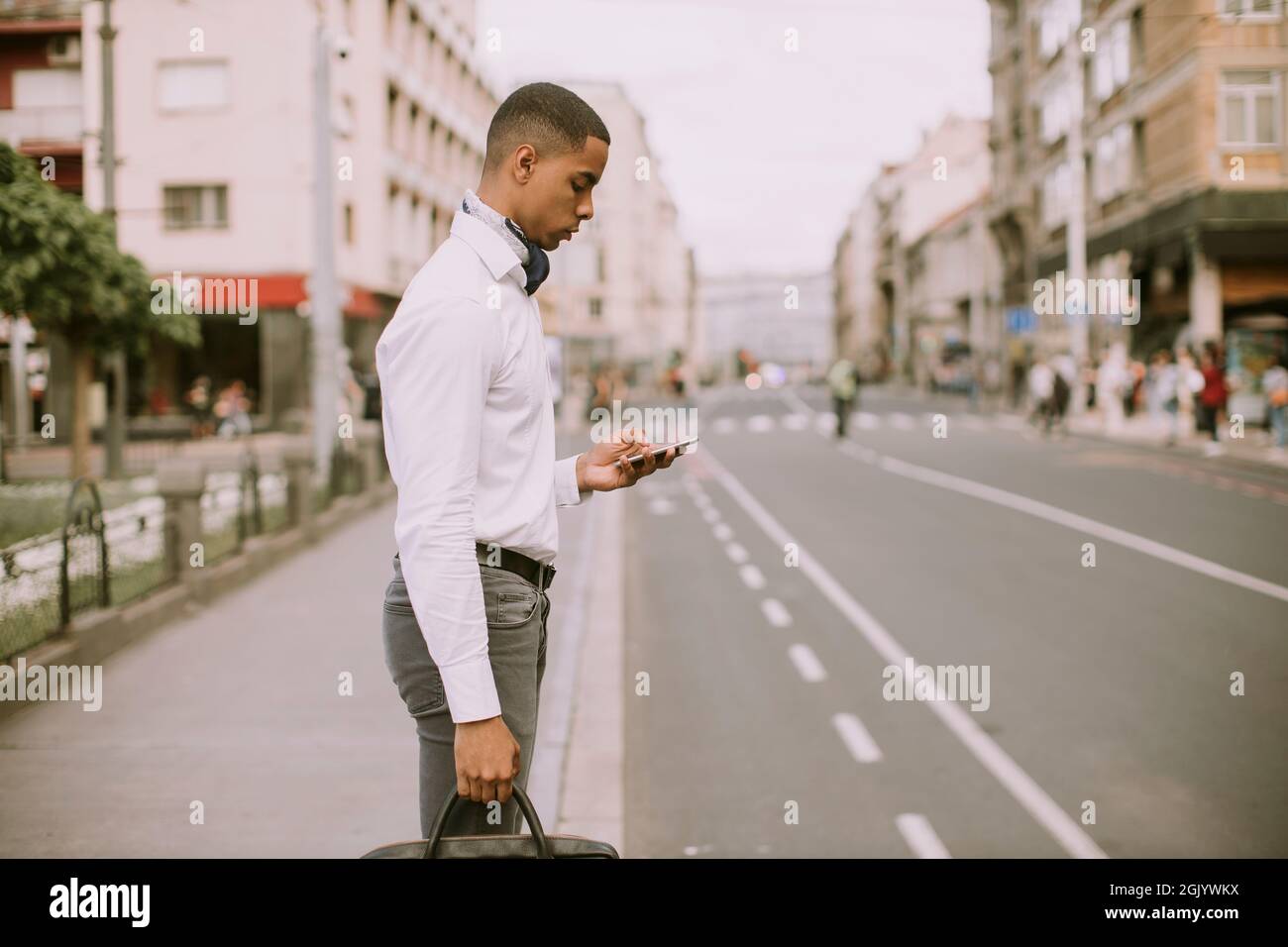 Bel giovane uomo d'affari afro-americano che usa un cellulare su una strada Foto Stock