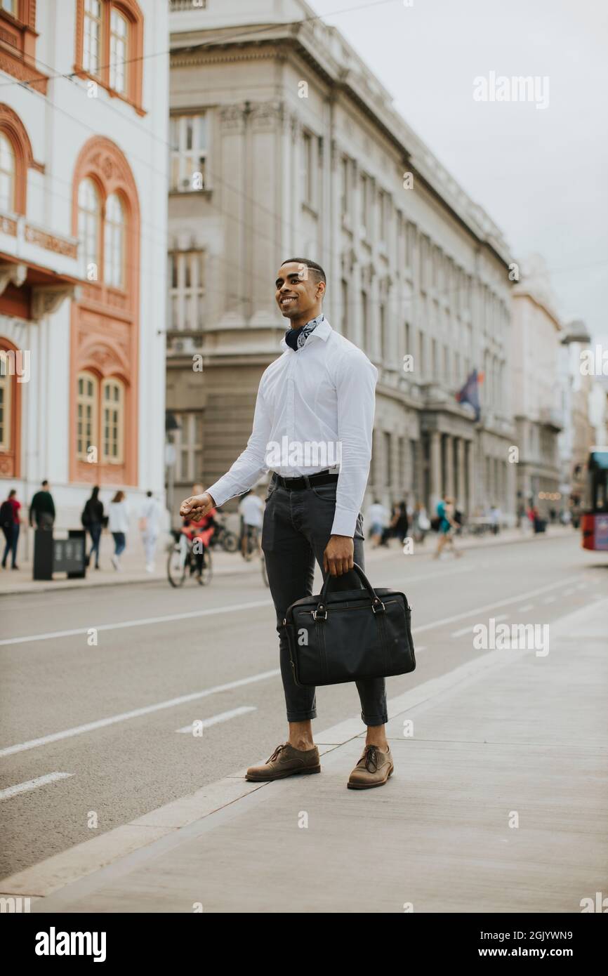 Bell'uomo d'affari afro-americano che ha in attesa di un taxi su un via Foto Stock