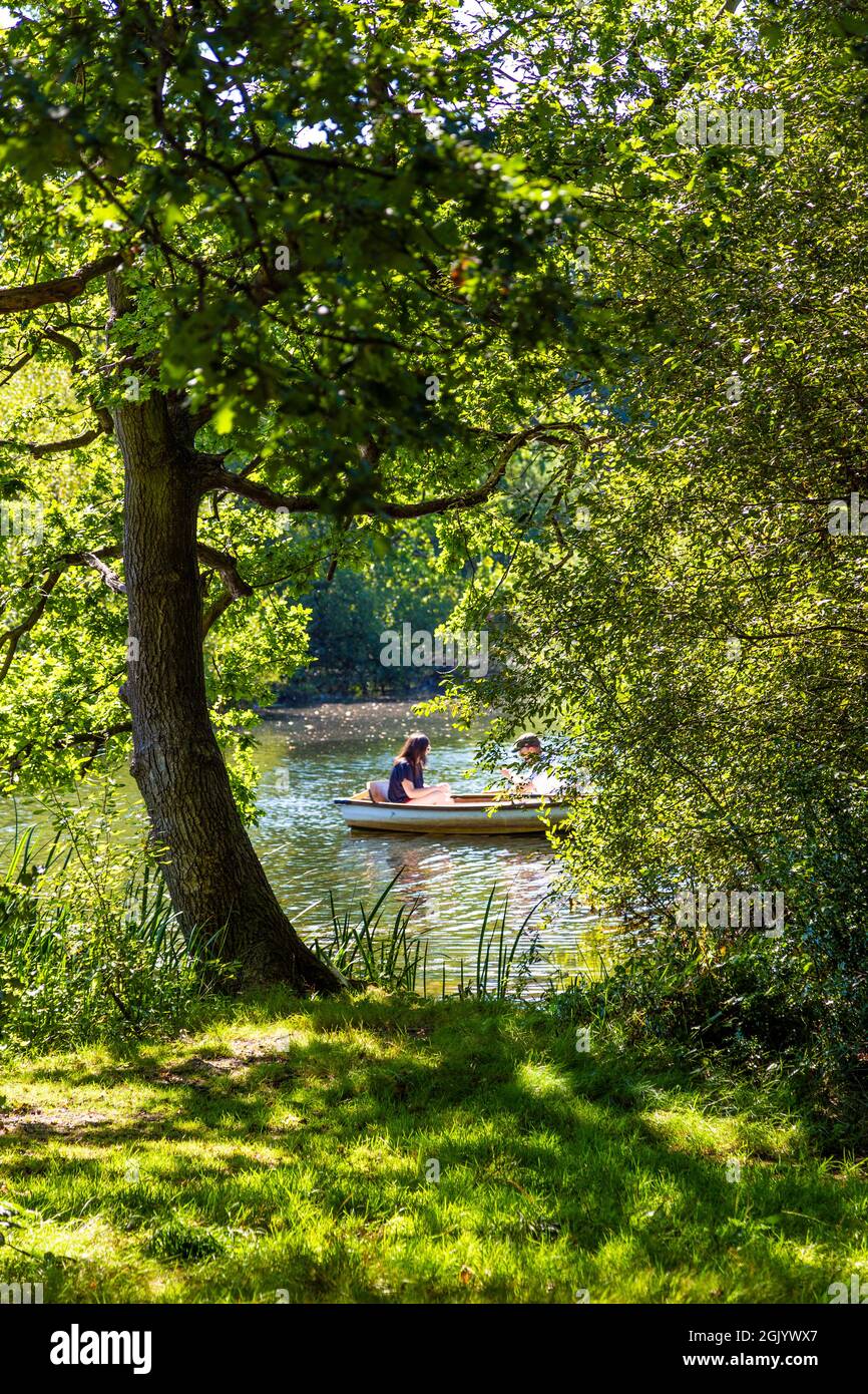 Due persone in barca di fila sul lago Hollow Pond in barca a Leyton Flats, Londra, Regno Unito Foto Stock