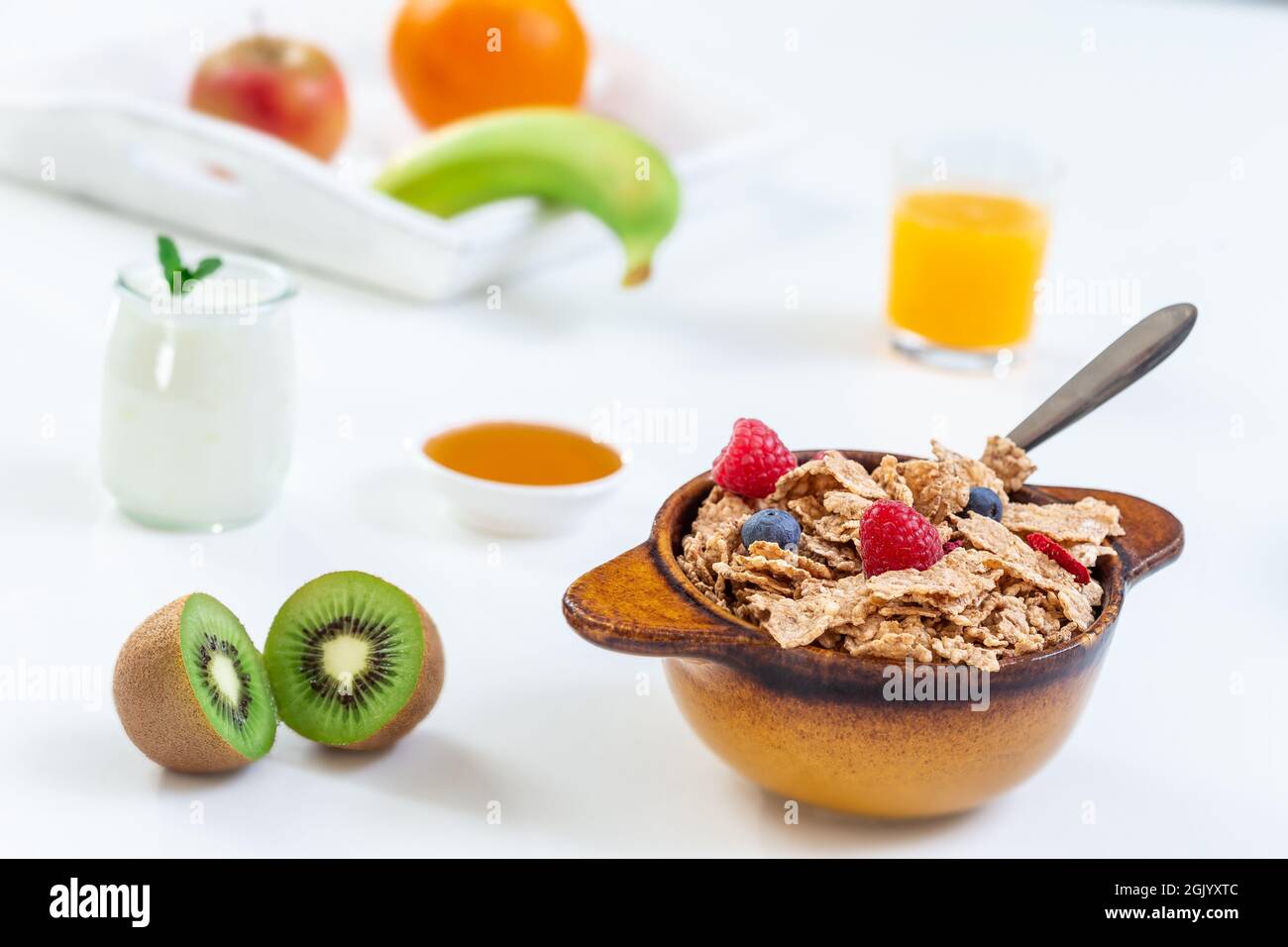 Colazione sana con ciotola di cereali, succo d'arancia, latte e frutta. Foto Stock