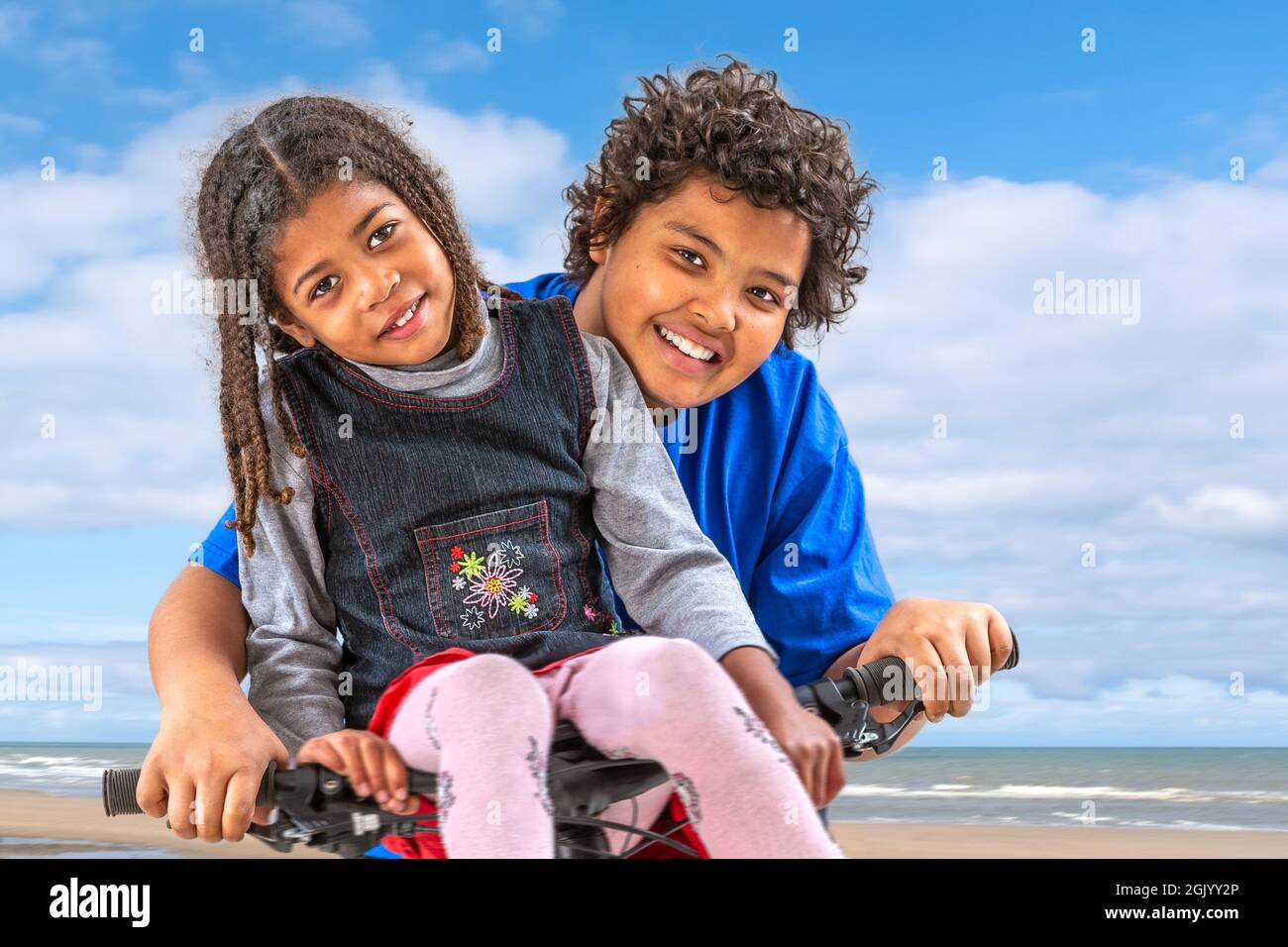 bambina di 6 anni sul manubrio e fratello di 10 anni in bicicletta. Foto Stock