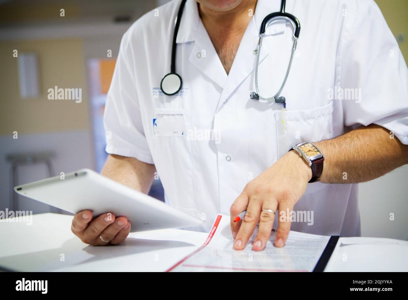 Medico che tiene la compressa e guarda la cartella paziente in ospedale. Foto Stock