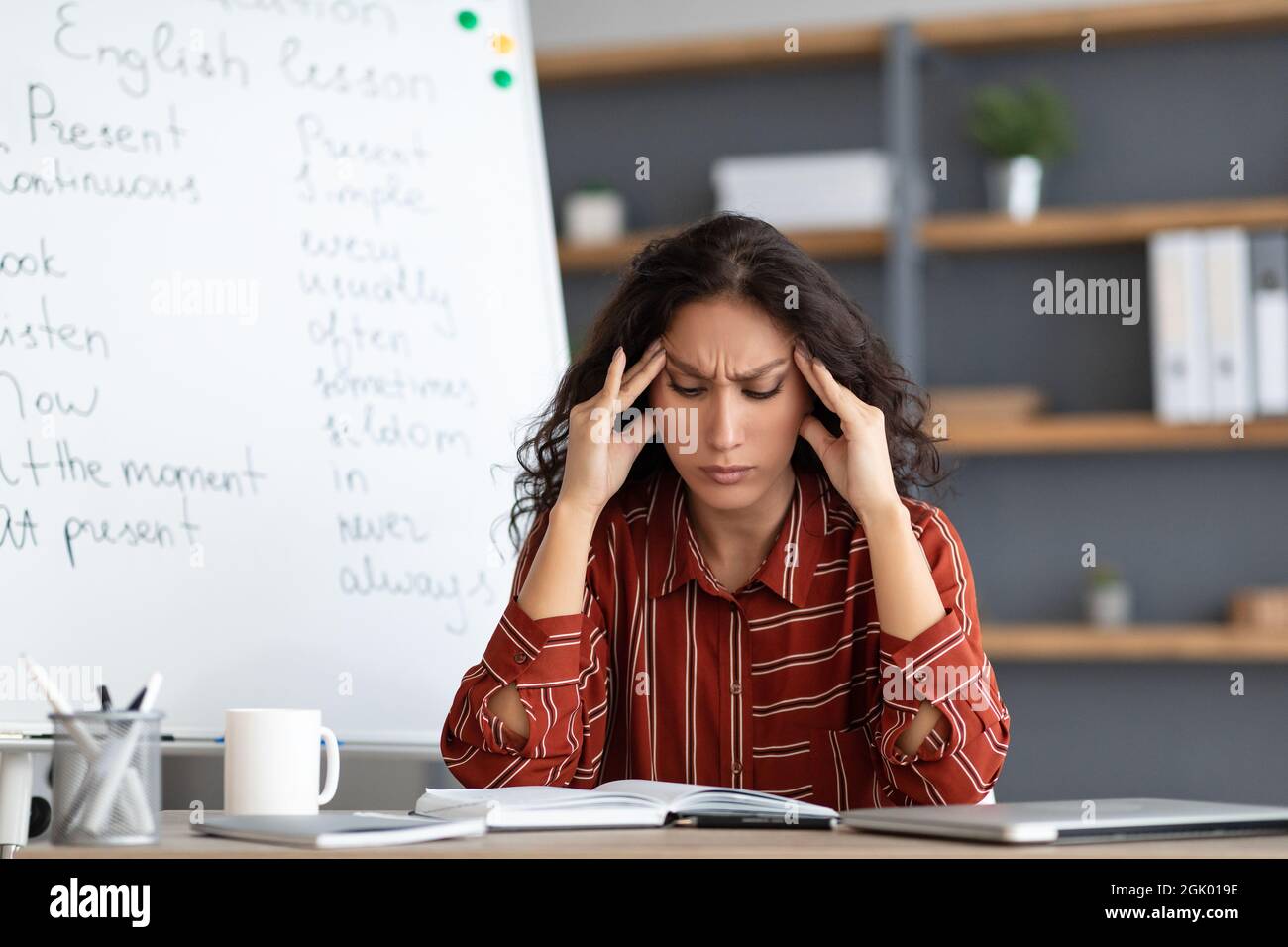 Annoiato e stanco insegnante toccare templi che soffrono di mal di testa Foto Stock