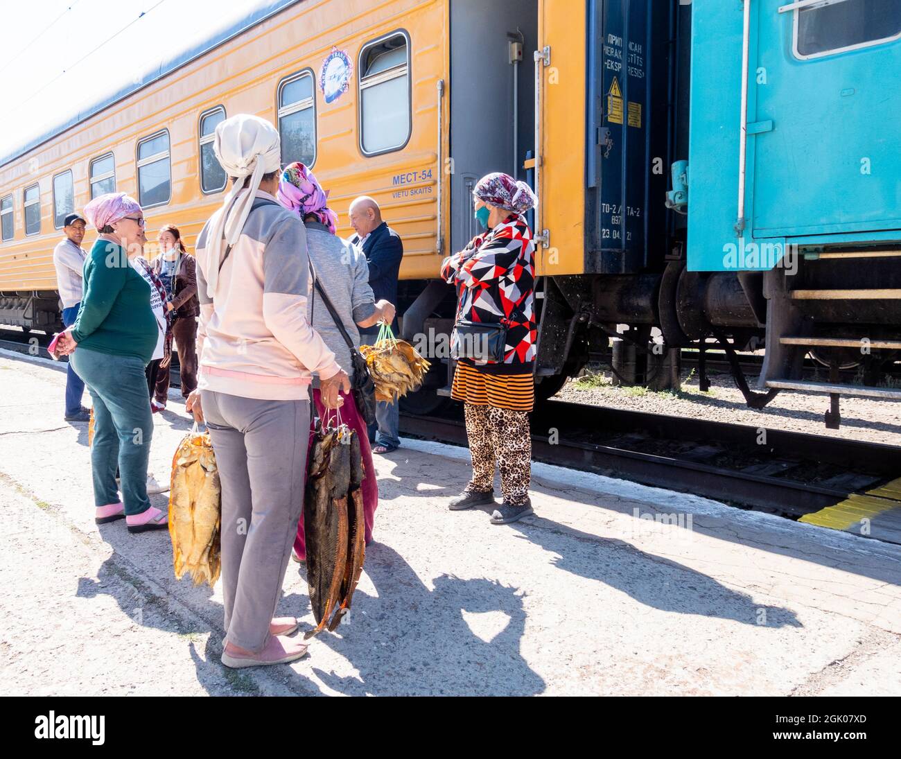 Donne che vendono pesce affumicato durante la sosta ai passeggeri del treno, stazione di Sary-Shagan, vicino al lago Balkhash, Kazakhstan, Asia centrale Foto Stock