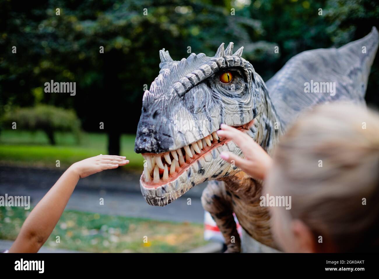 Bucarest, Romania - 29 agosto 2021: Un uomo in costume da dinosauro carnivoro cammina tra le persone e li lascia accarezzare durante un evento all'aperto Foto Stock
