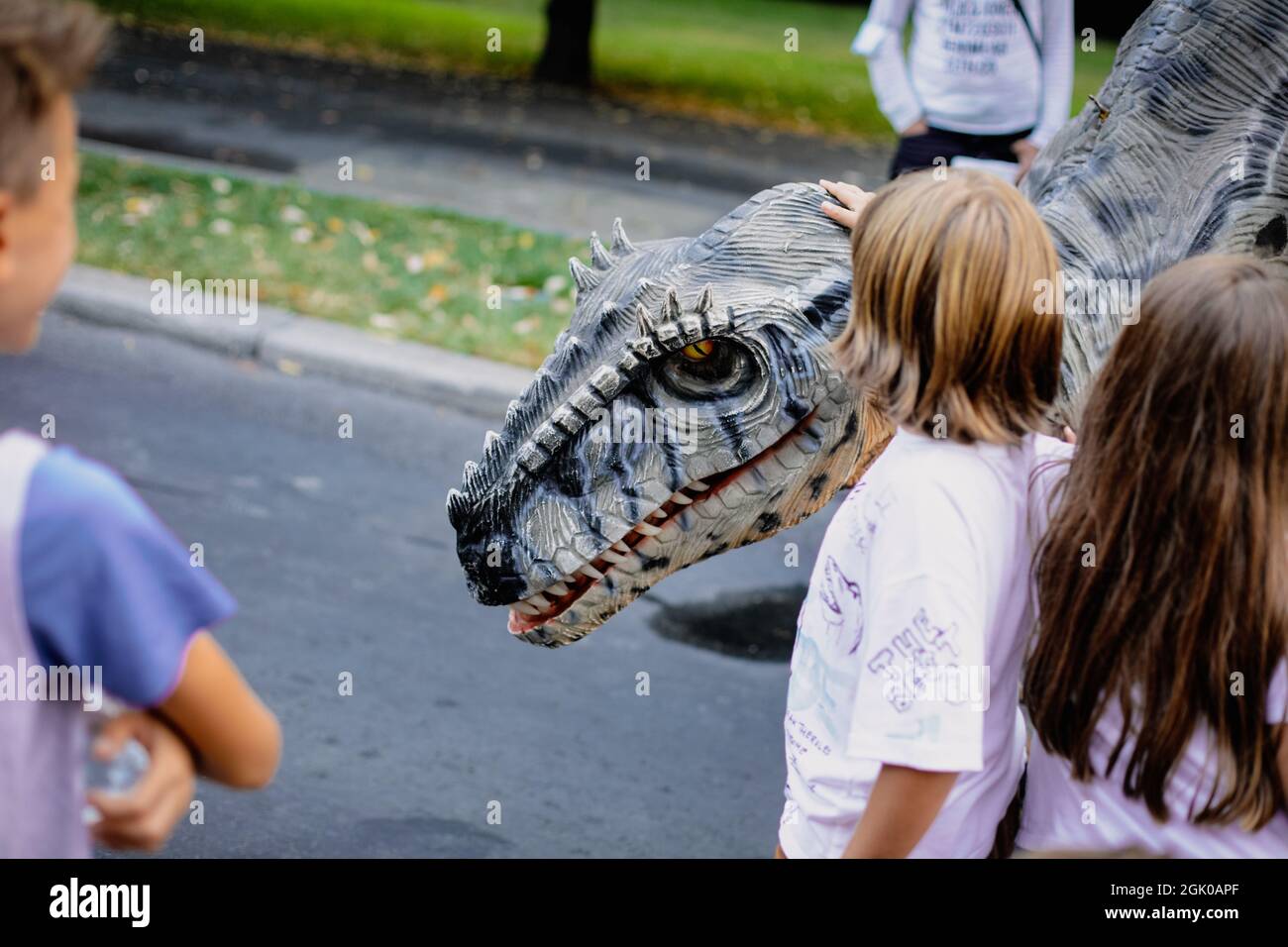 Bucarest, Romania - 29 agosto 2021: Un uomo in costume da dinosauro carnivoro cammina tra le persone e li lascia accarezzare durante un evento all'aperto Foto Stock