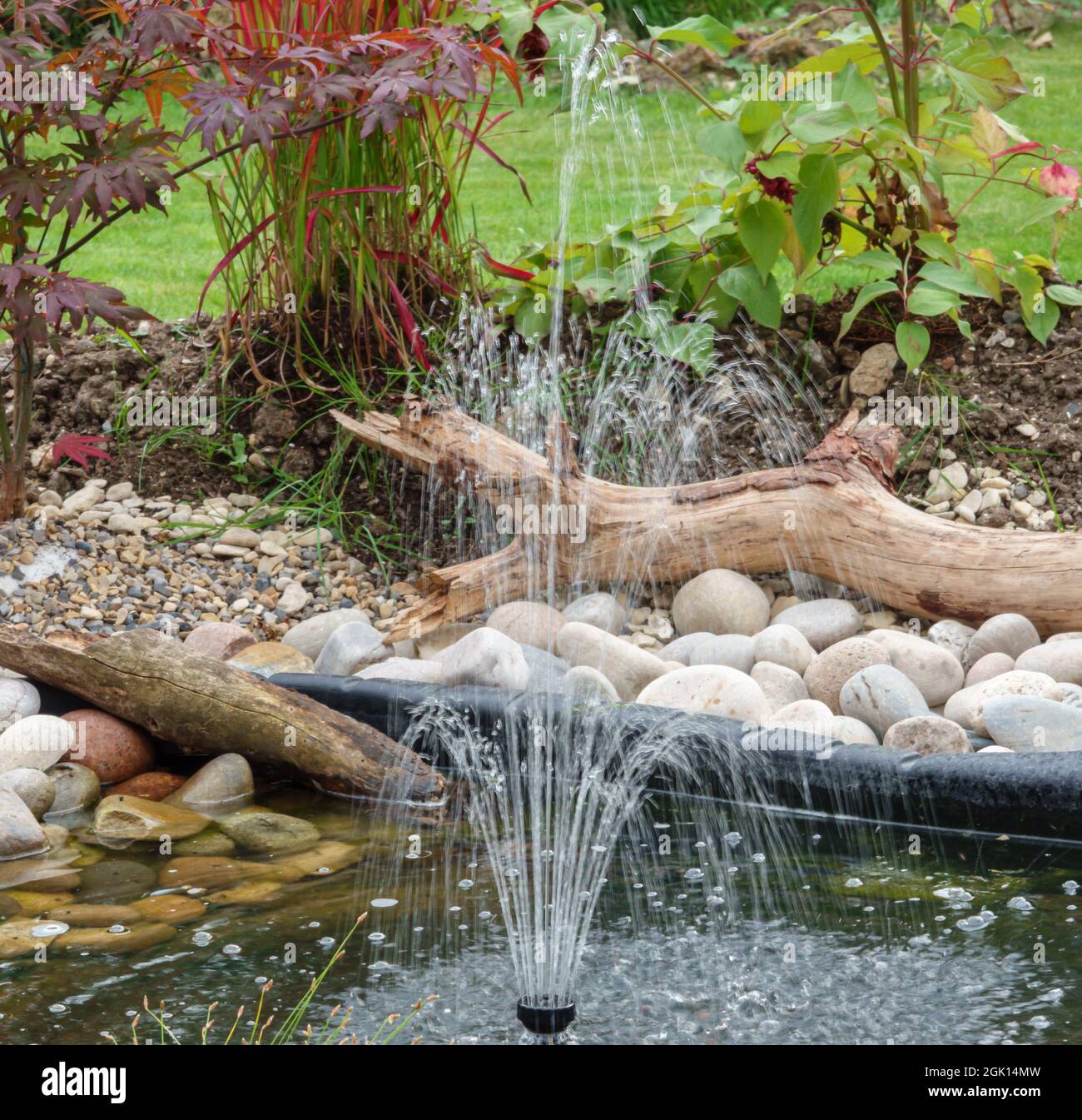 una fontana d'acqua a energia solare del giardino getta mini getti d'acqua  skywards per tornare a cascata nel laghetto giardino Foto stock - Alamy