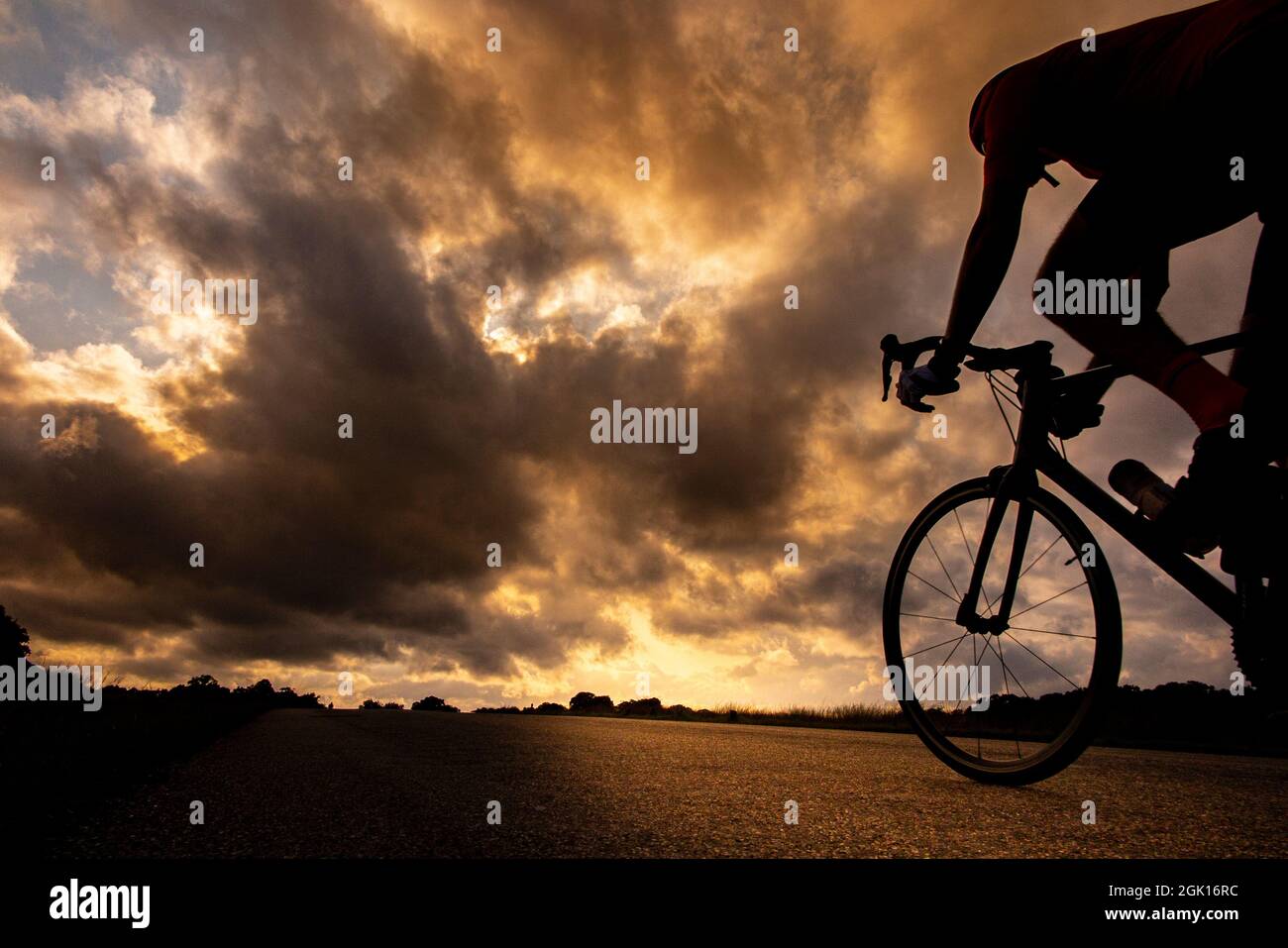 Cieli spettacolari mentre il sole tramonta a Richmond Park e un ciclista si dirige a casa Foto Stock
