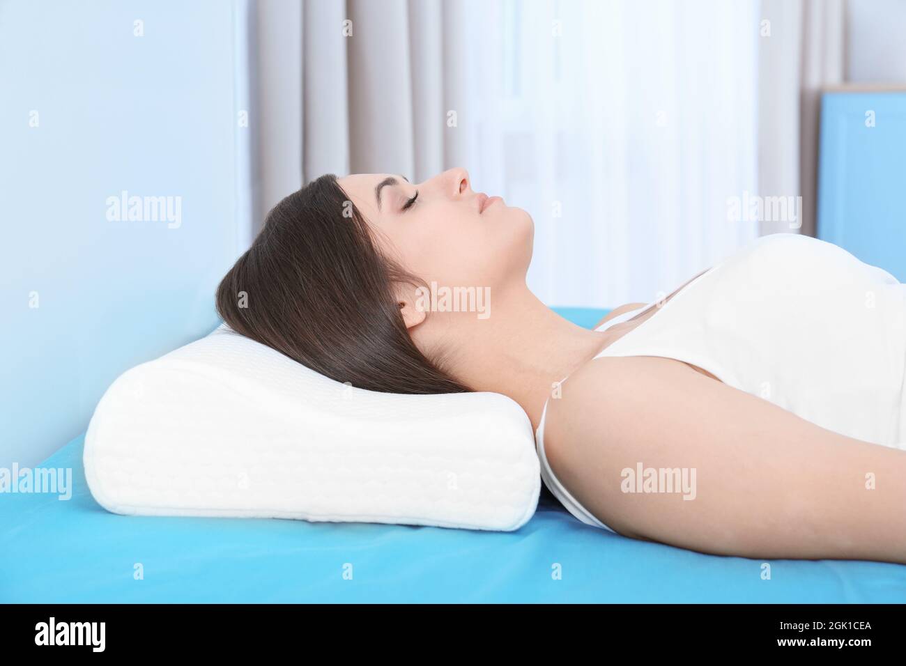 Giovane donna che dorme a letto con cuscino ortopedico a casa