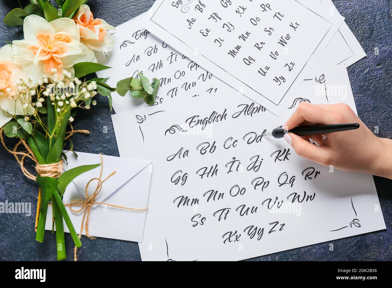 Donna che scrive alfabeto inglese su sfondo scuro Foto Stock