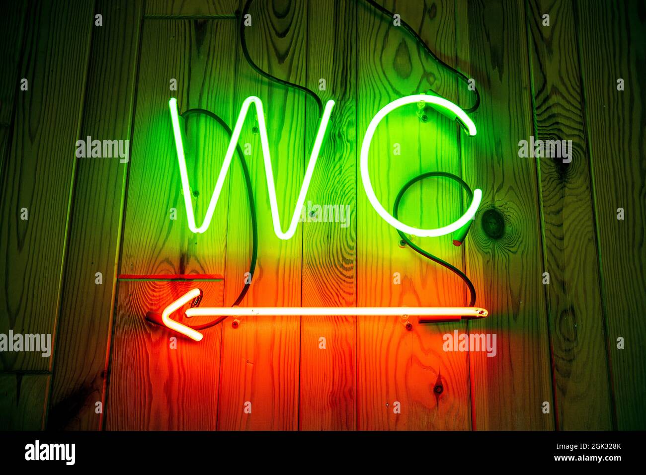 Cartello al neon WC su parete di legno. WC, lancetta al neon Foto Stock