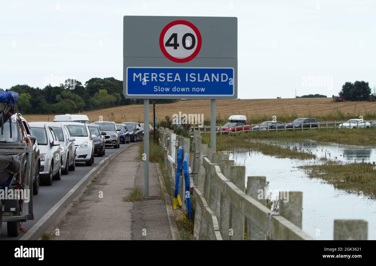 Il traffico è in attesa di venire fuori Mersea Island in Essex a causa dell'alta marea che copre lo Strood, l'unica strada che collega l'isola alla terraferma. Foto Stock