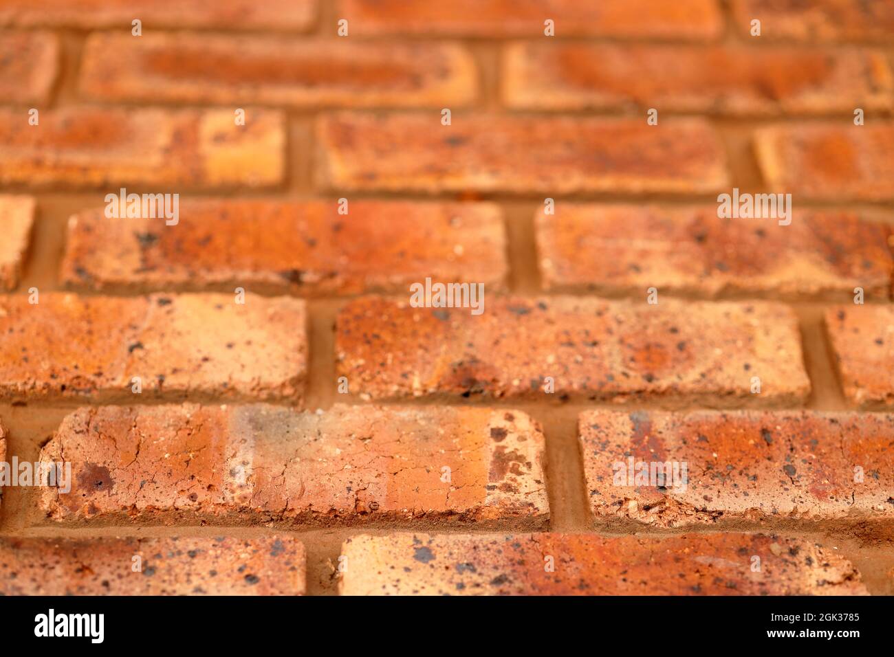 Primo piano di muro fatto di mattoni rossi con inclusioni nere sfondo mattoni con texture Foto Stock