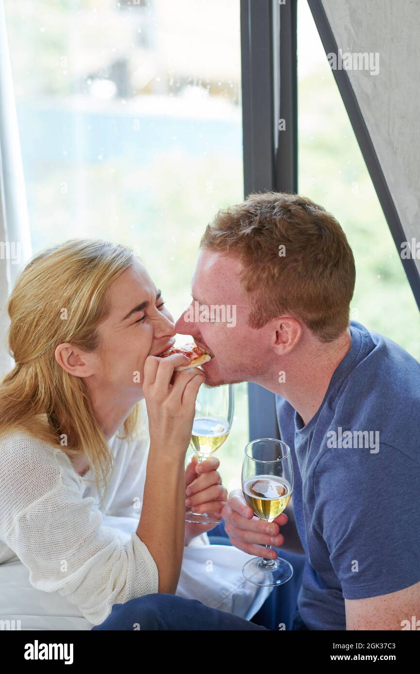 Giovane coppia innamorata di condividere l'ultimo pezzo di pizza quando si fa una cena romantica a casa Foto Stock