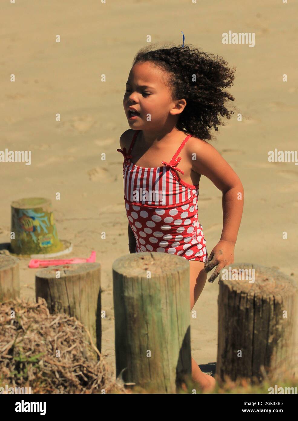 Carina ragazza africana con capelli ricci che giocano su una spiaggia Foto Stock
