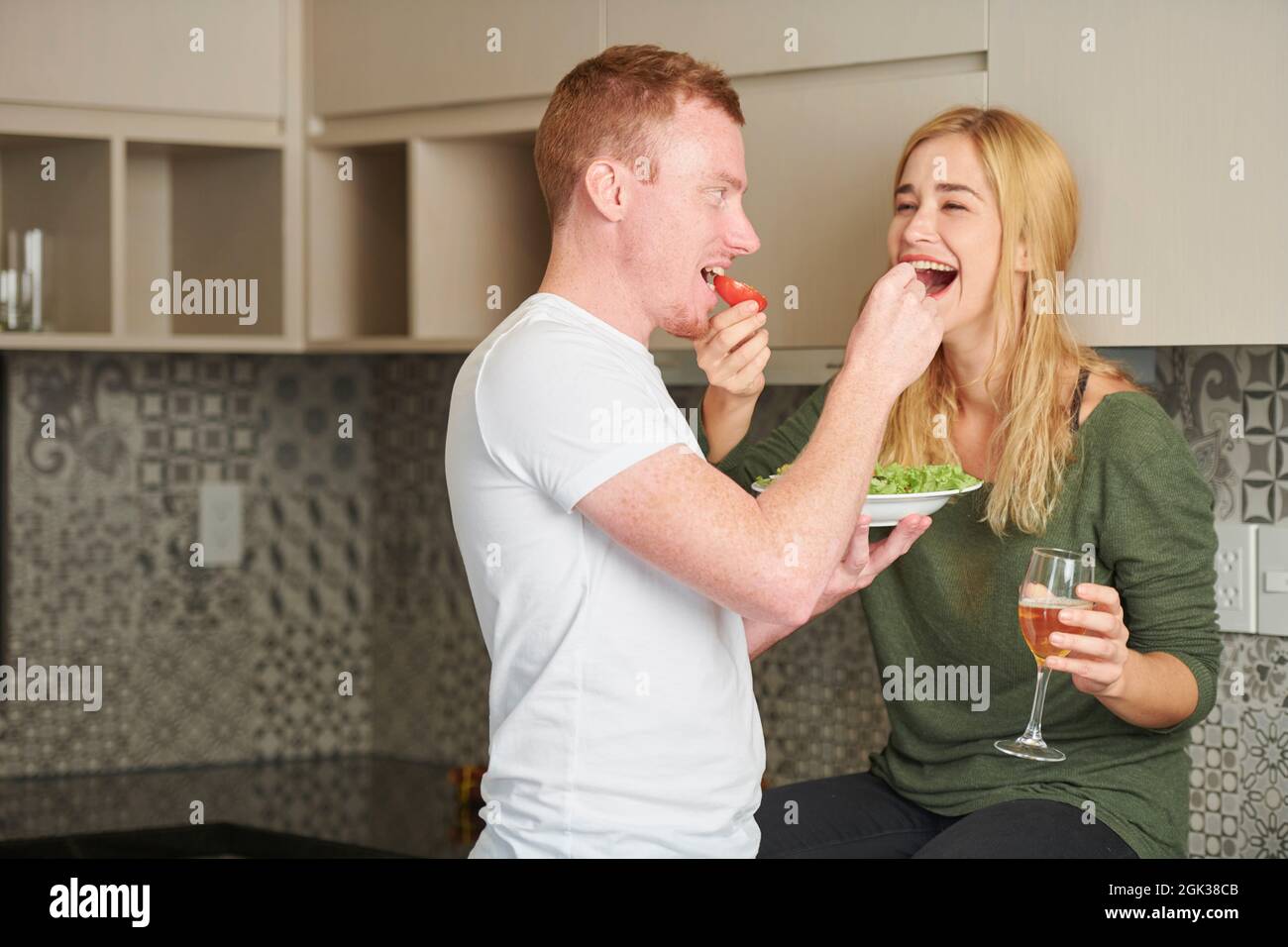 Gioiosa coppia giovane in amore che si nutrono quando si ha una cena romatica a casa Foto Stock