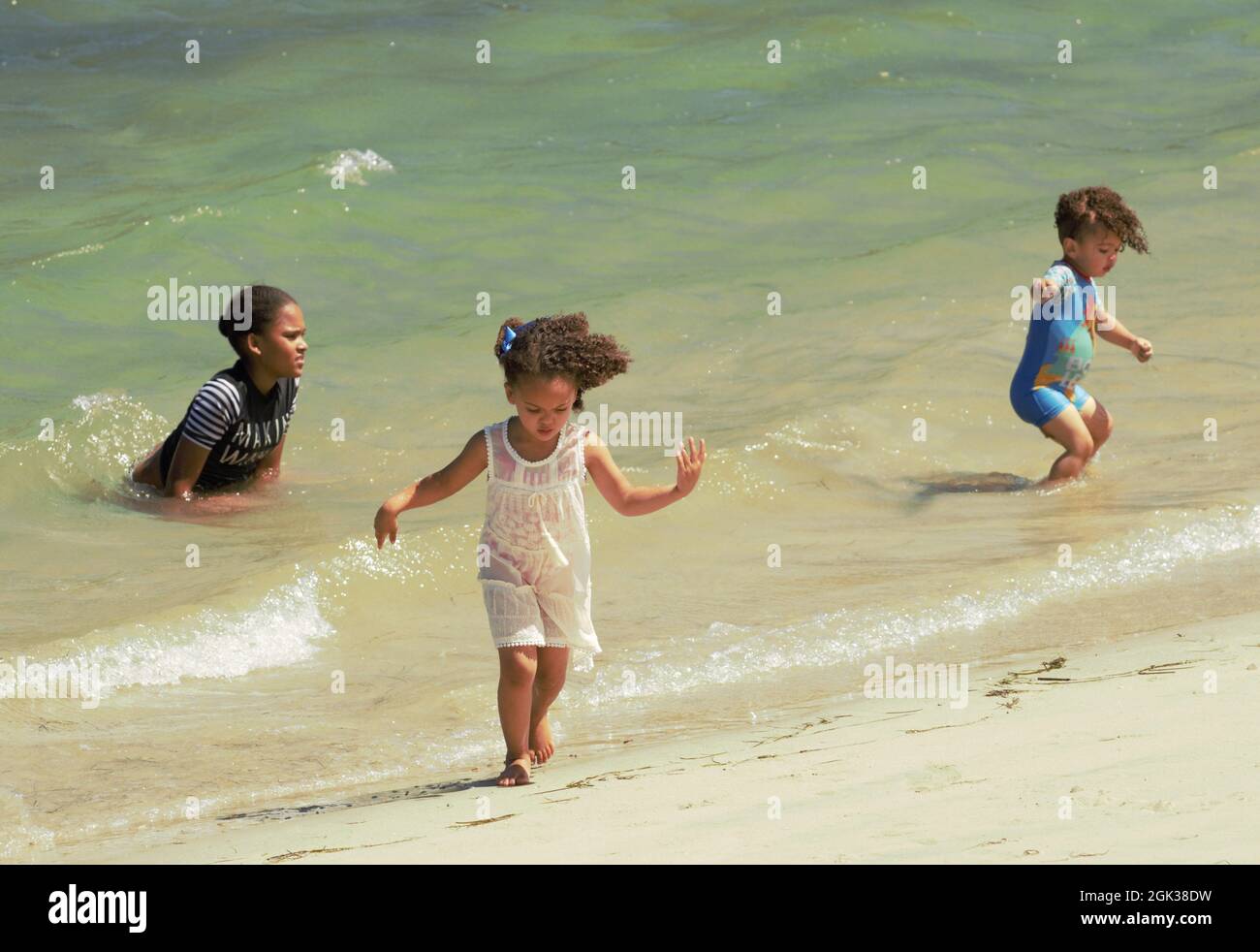 Carina ragazza africana con capelli ricci e i suoi due piccoli fratelli che giocano su una spiaggia Foto Stock