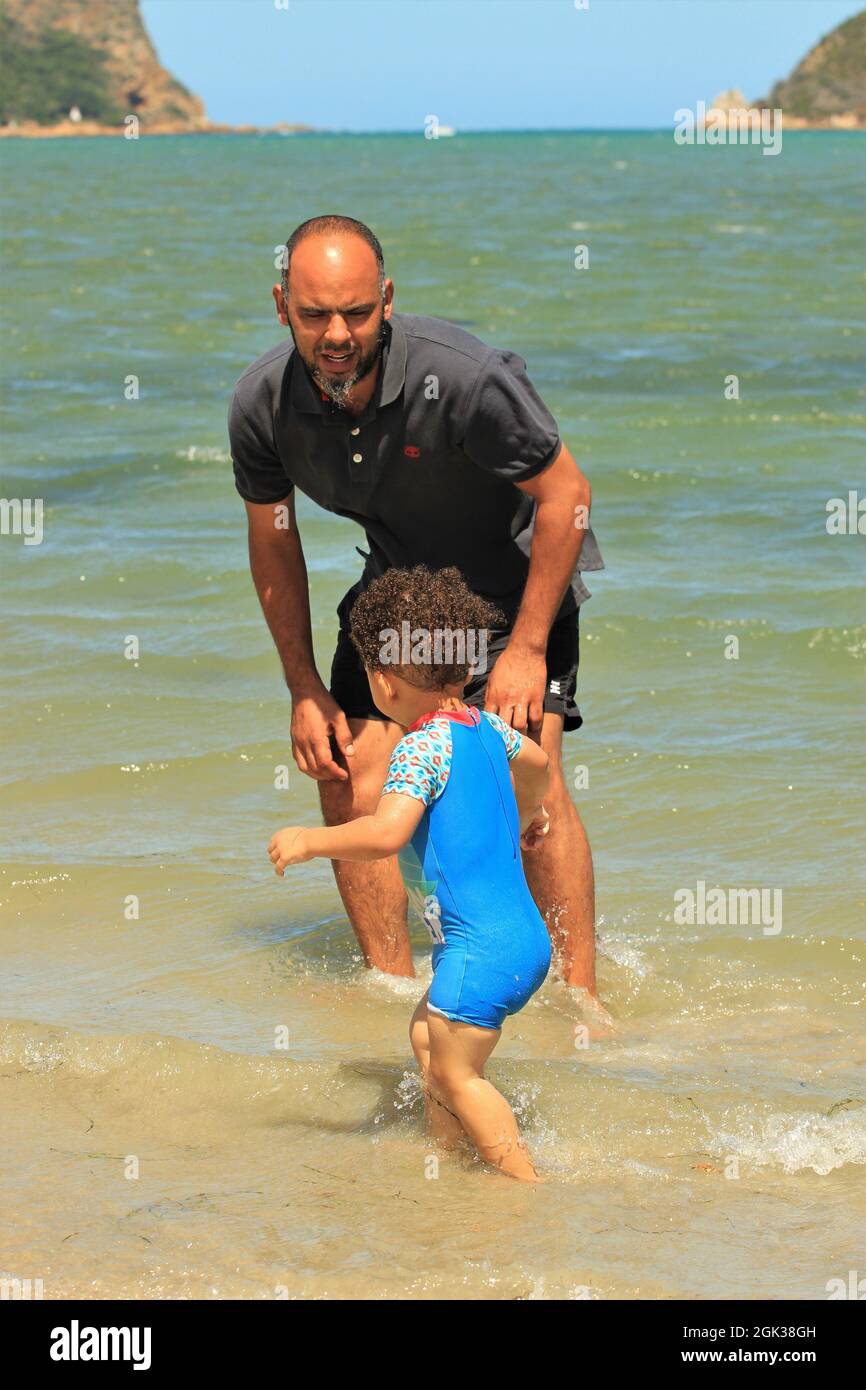 Giovane padre africano che gioca con il bambino su una spiaggia Foto Stock