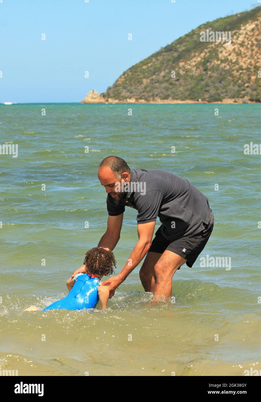 Giovane padre africano che gioca con il bambino su una spiaggia Foto Stock