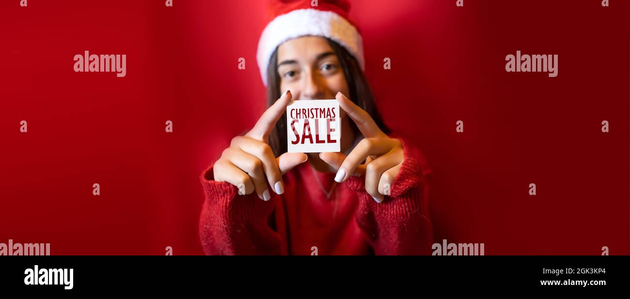 Promozione di Natale in mano a una ragazza. Pubblicità per siti web e social. Sfondo rosso e atmosfera natalizia. Facile personalizzazione. Foto Stock