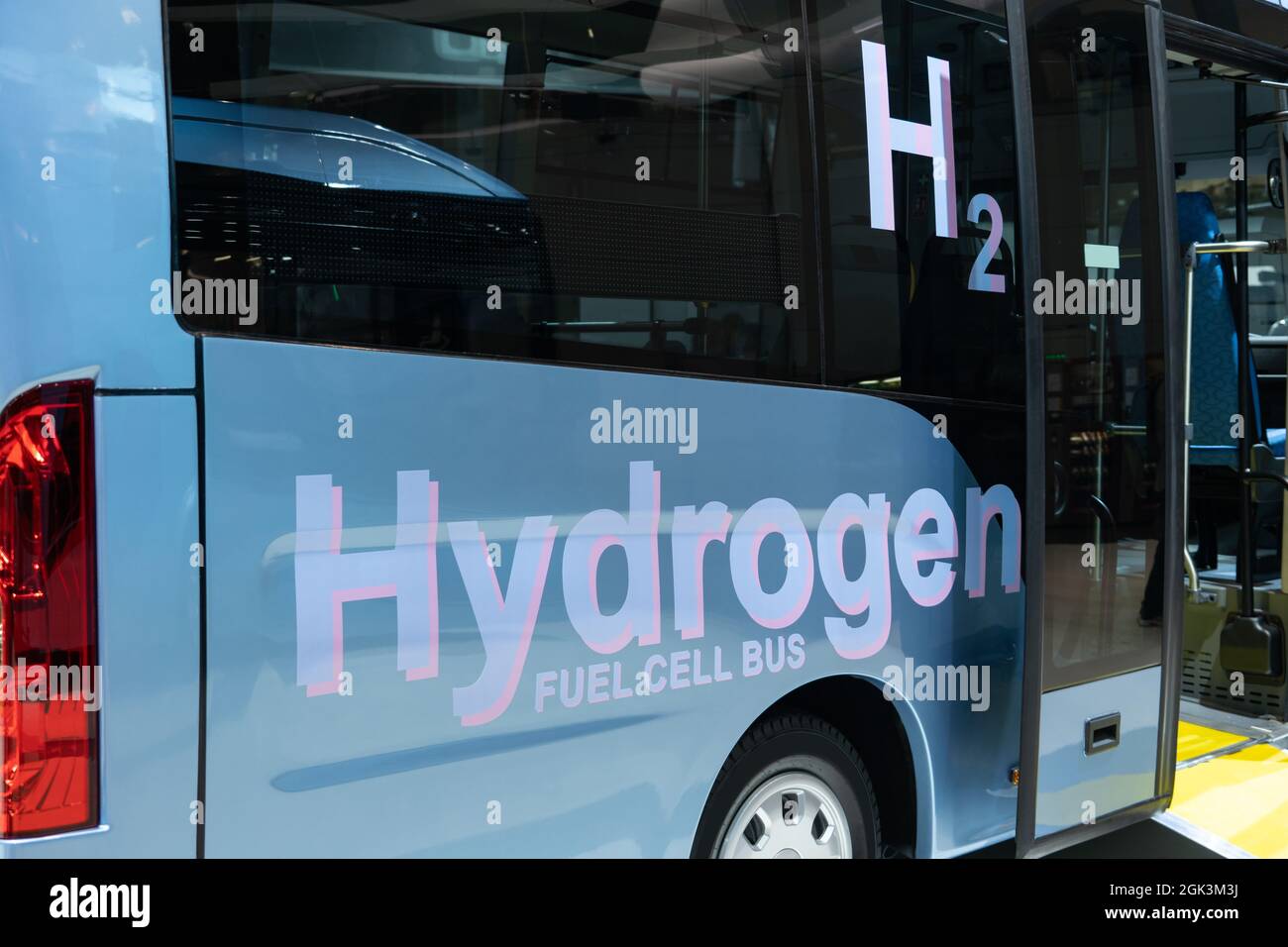Bus blu con iscrizione BUS CELLA FUELL IDROGENO e simbolo H2 su una scheda. Veicolo ecologico Foto Stock