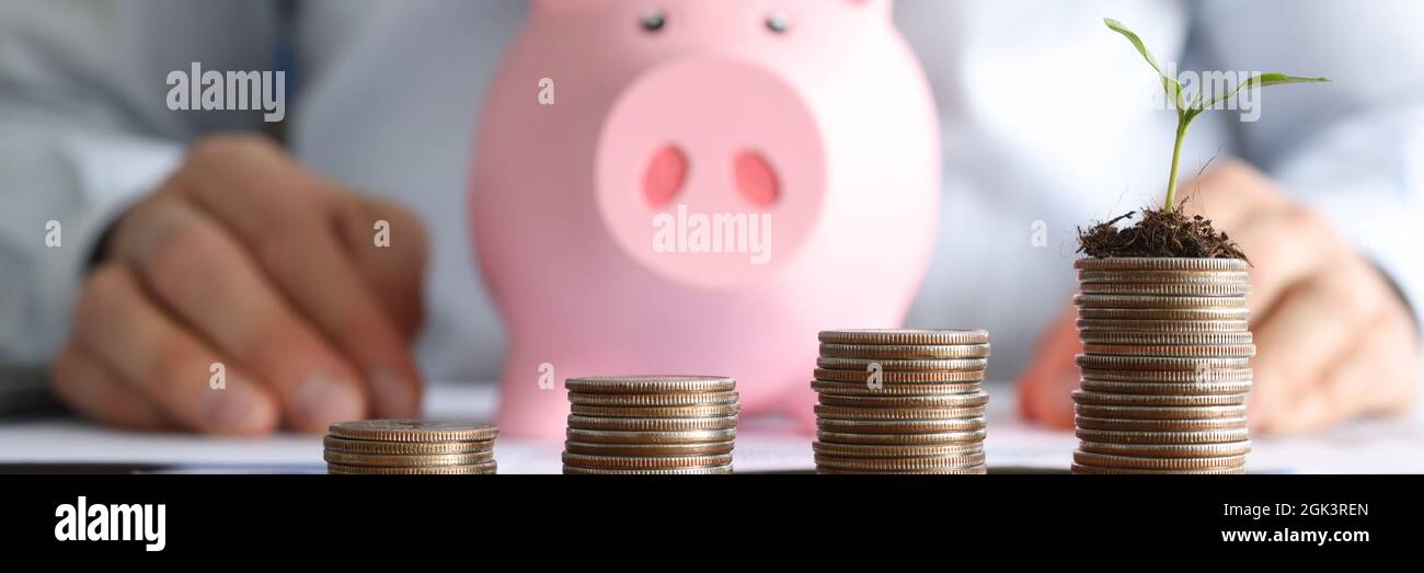Davanti a uomini d'affari sono cilindri di monete e rosa porcellino banca Foto Stock