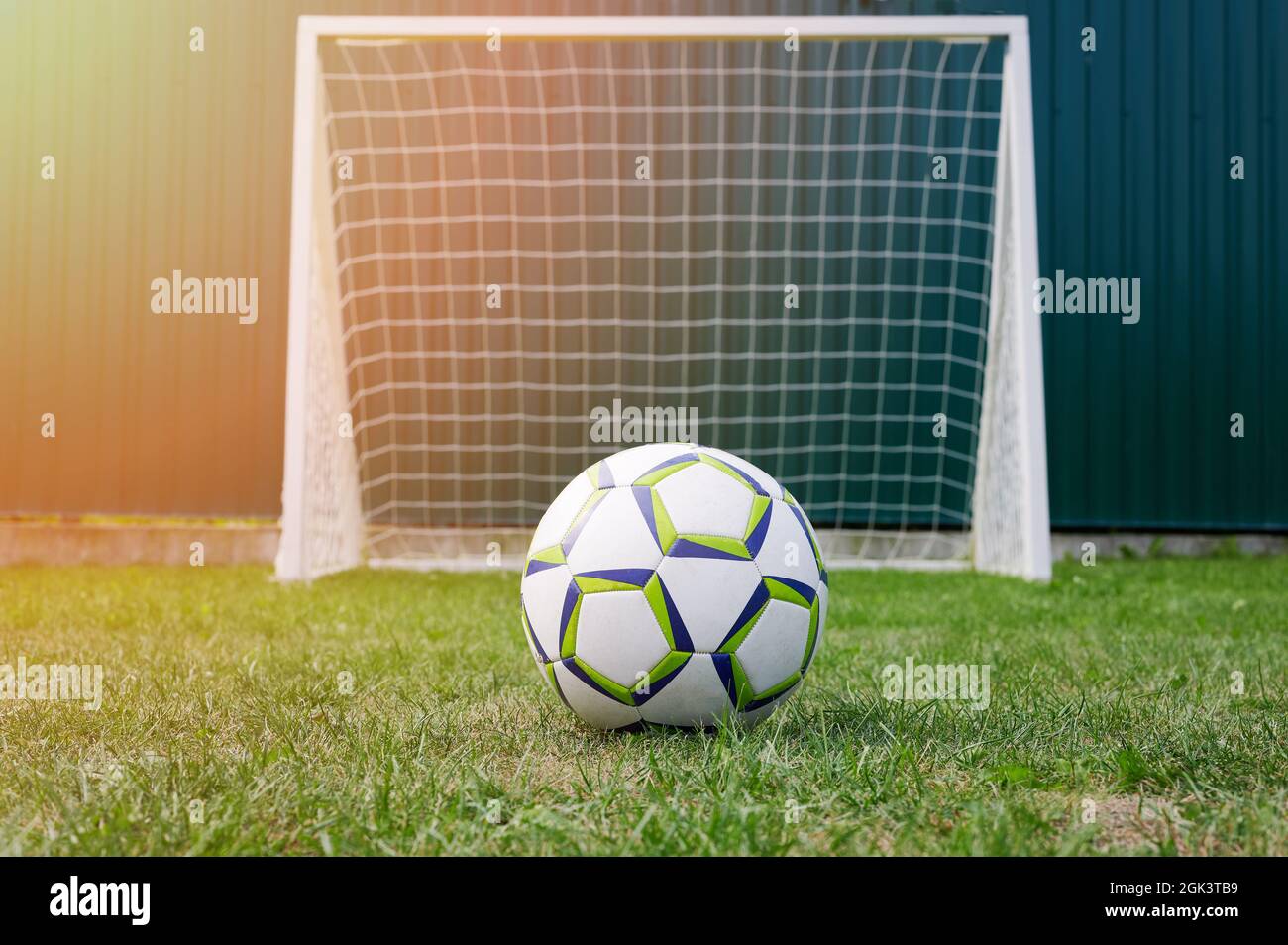 Pallone da calcio su erba verde di fronte al cancello con rete Foto Stock