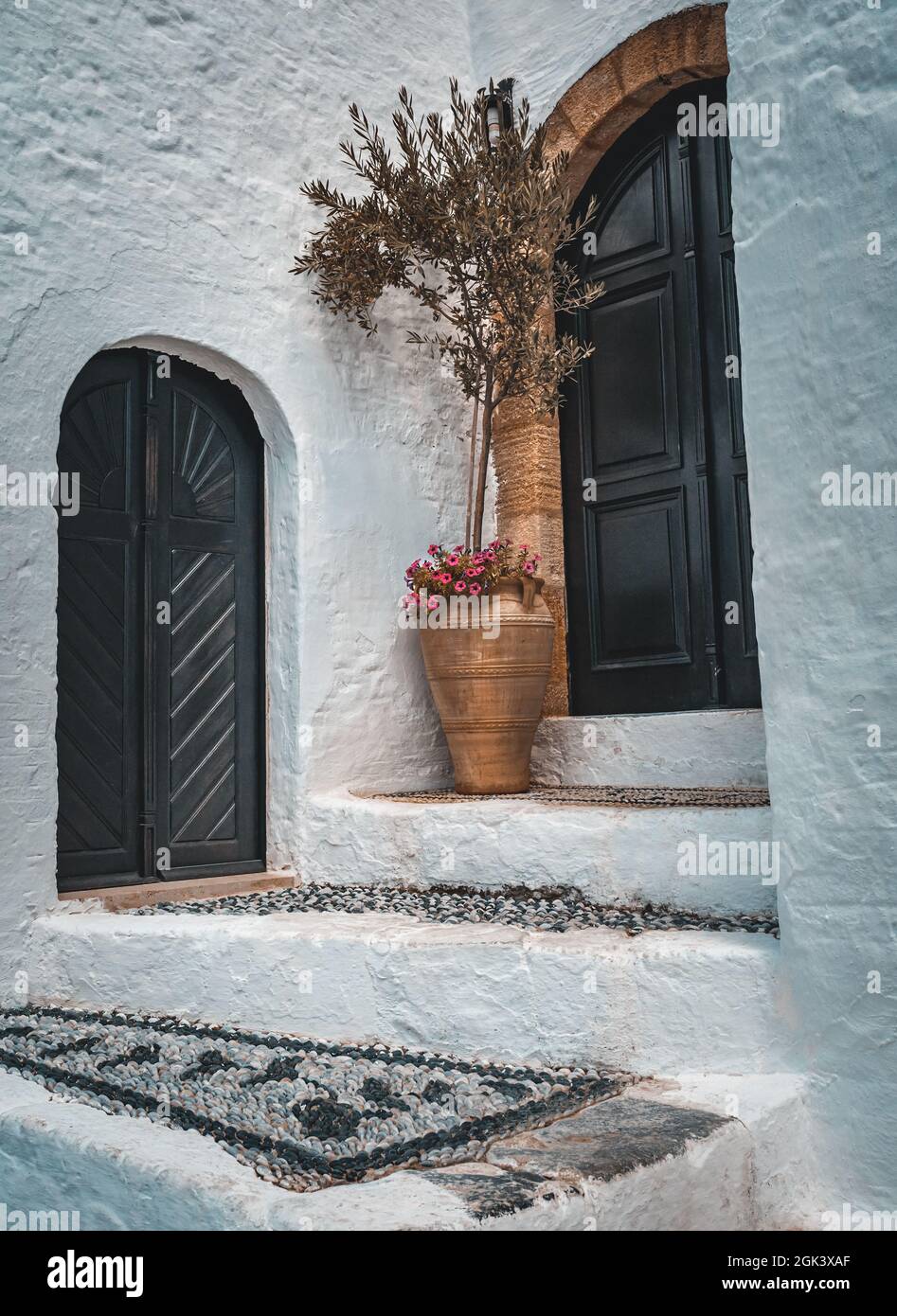 Tipica facciata greca. Belle pareti bianche. Scale coperte con motivo  tradizionale. Bellissimi poeti con olivo e fiori Foto stock - Alamy