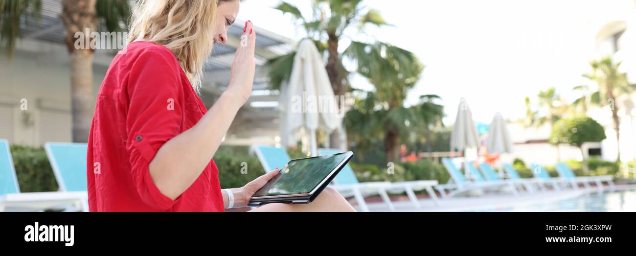 Donna si saluta felicemente con i soci di affari della mano sul tablet mentre sedendo in piscina Foto Stock